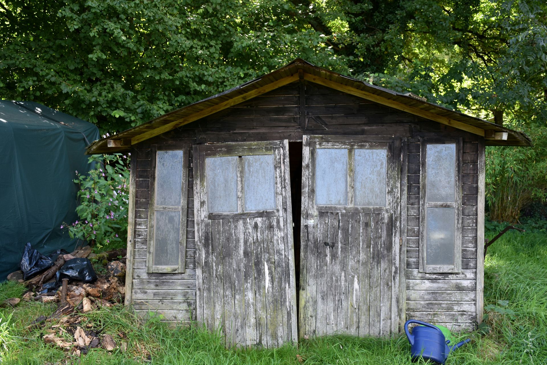 A weathered wooden shed with glass windows